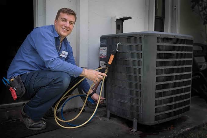 HVAC technician connecting service gauges to a residential outdoor condenser