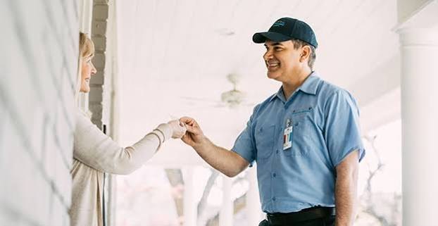 Homeowner greeting an HVAC service technician at the front door
