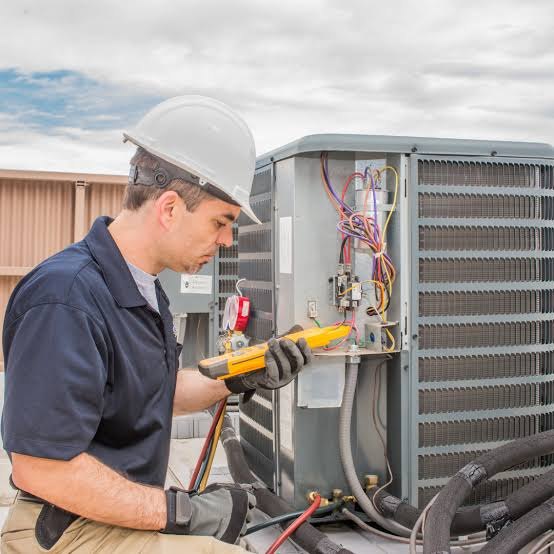 HVAC technician using a meter to troubleshoot an outdoor air conditioning unit