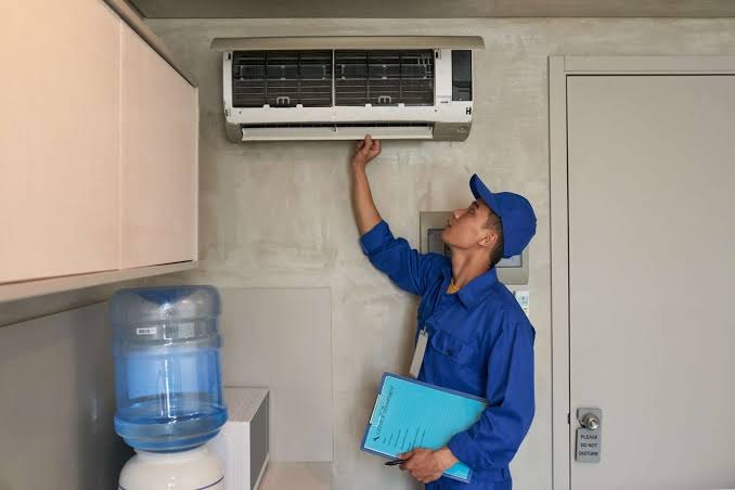 Technician inspecting a wall-mounted indoor cooling unit